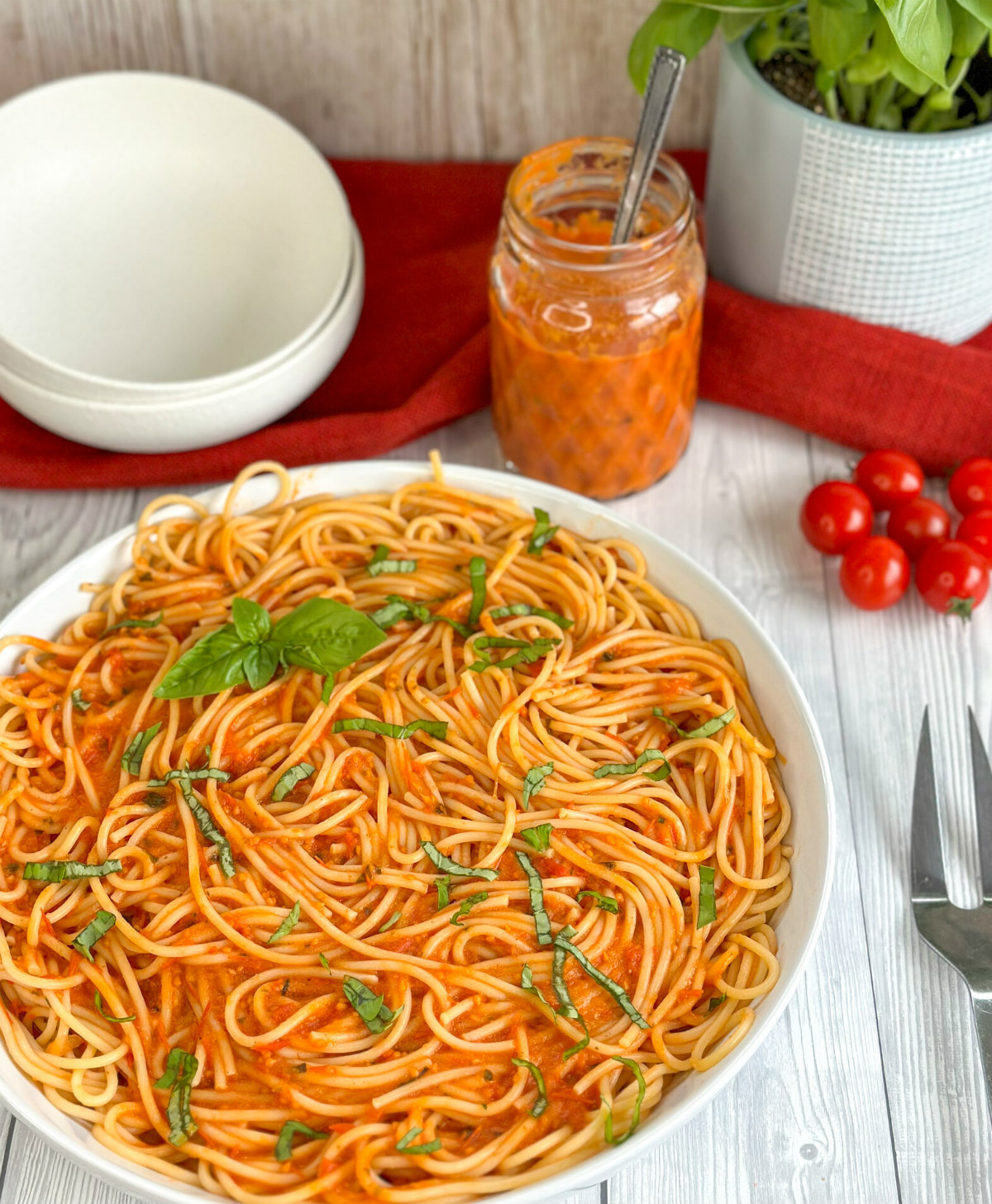 Bowl of spaghetti with homemade cherry tomato and basil pasta sauce and a jar of pasta sauce