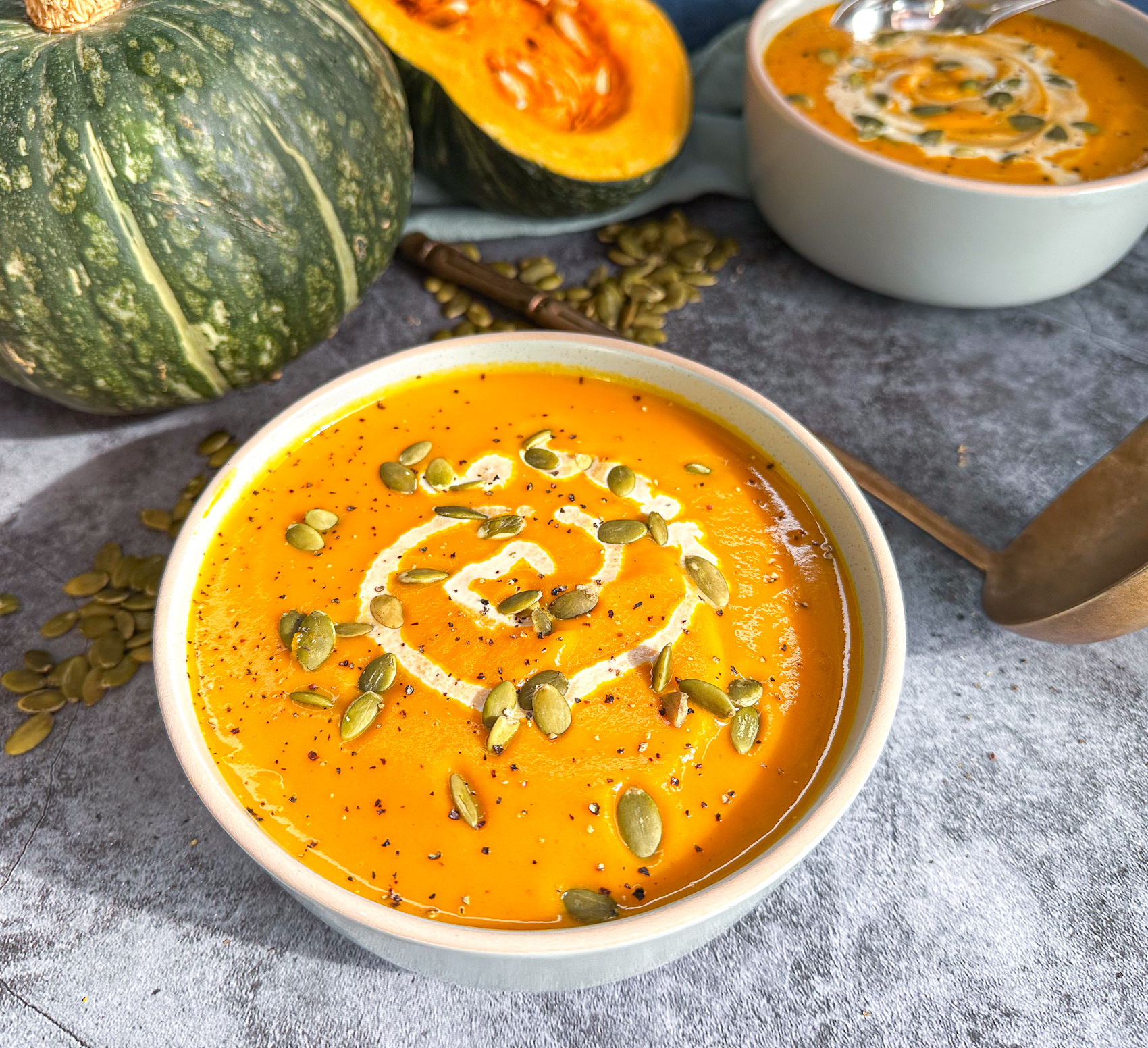 Easy Slow Cooker Pumpkin Soup in a bowl served with a swirl of cream and pumpkin seeds