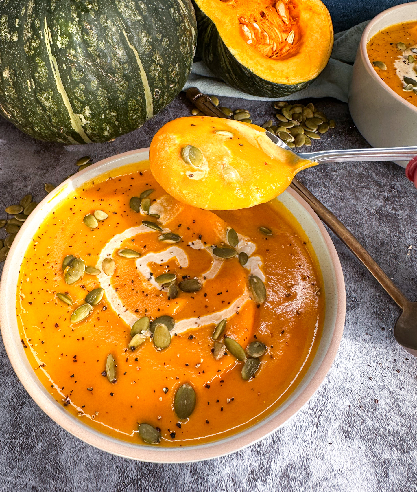 A soup spoon scooping up smooth and creamy pumpkin soup
