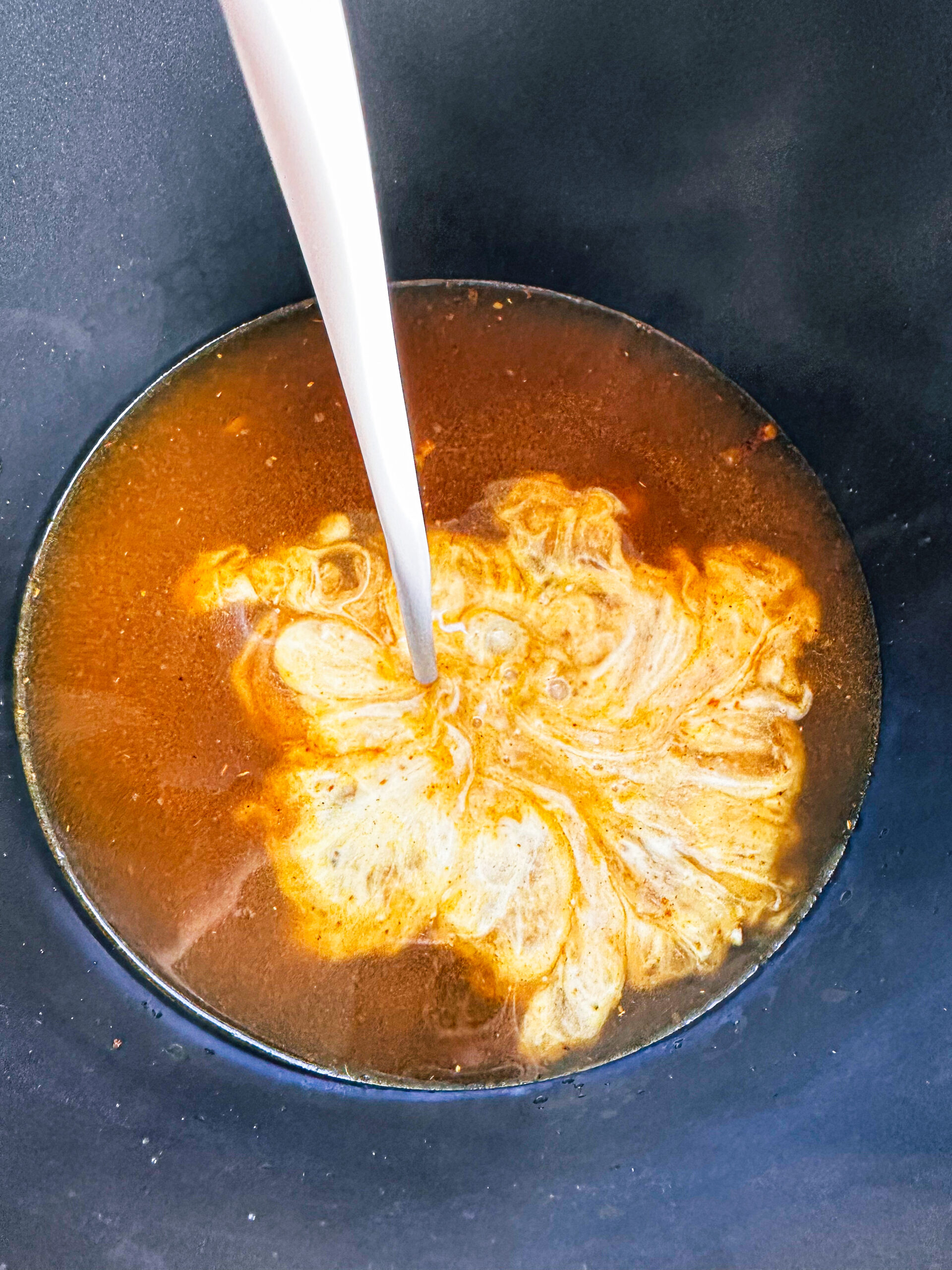 Pouring cream into the curry sauce
