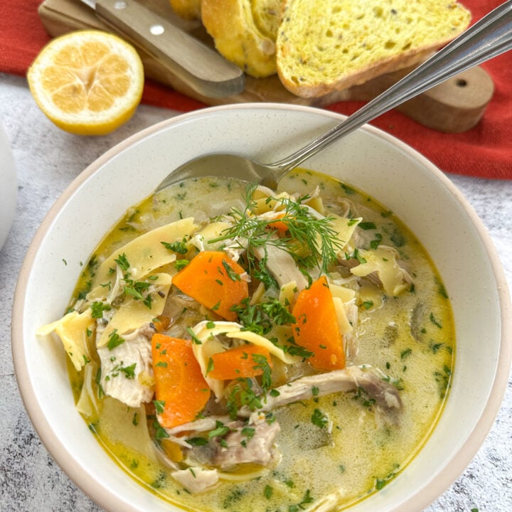 Bowl filled with creamy slow cooker chicken noodle soup garnished with fresh parsley