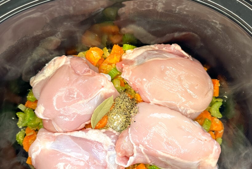 Raw chicken in the slow cooking on a pile of vegetables