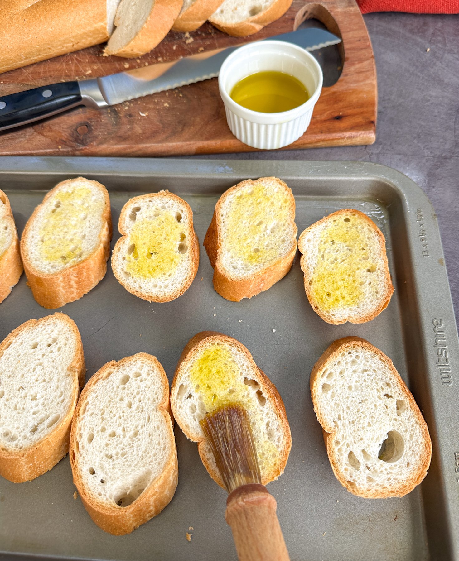 spreading the sliced baguette with some olive oil before baking