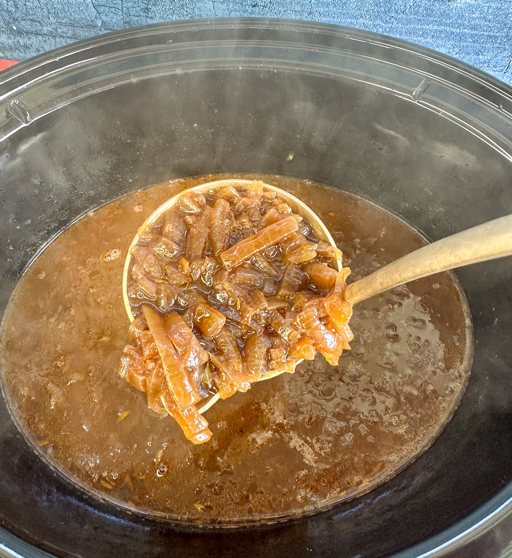 Ladle holding up steaming French onion soup
