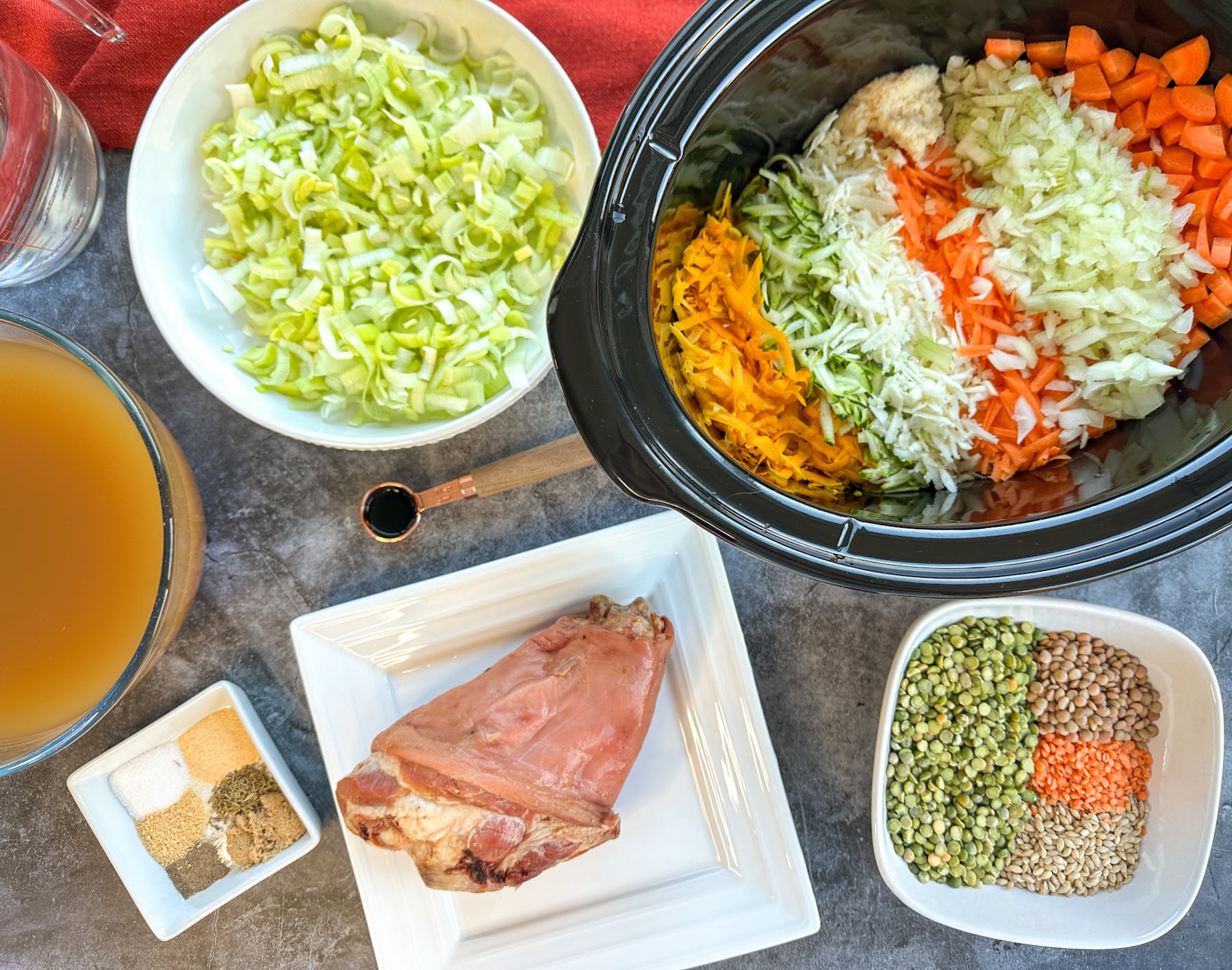 ingredients to prepare ham hock and vegetable soup including spices, herbs, broth and lentils