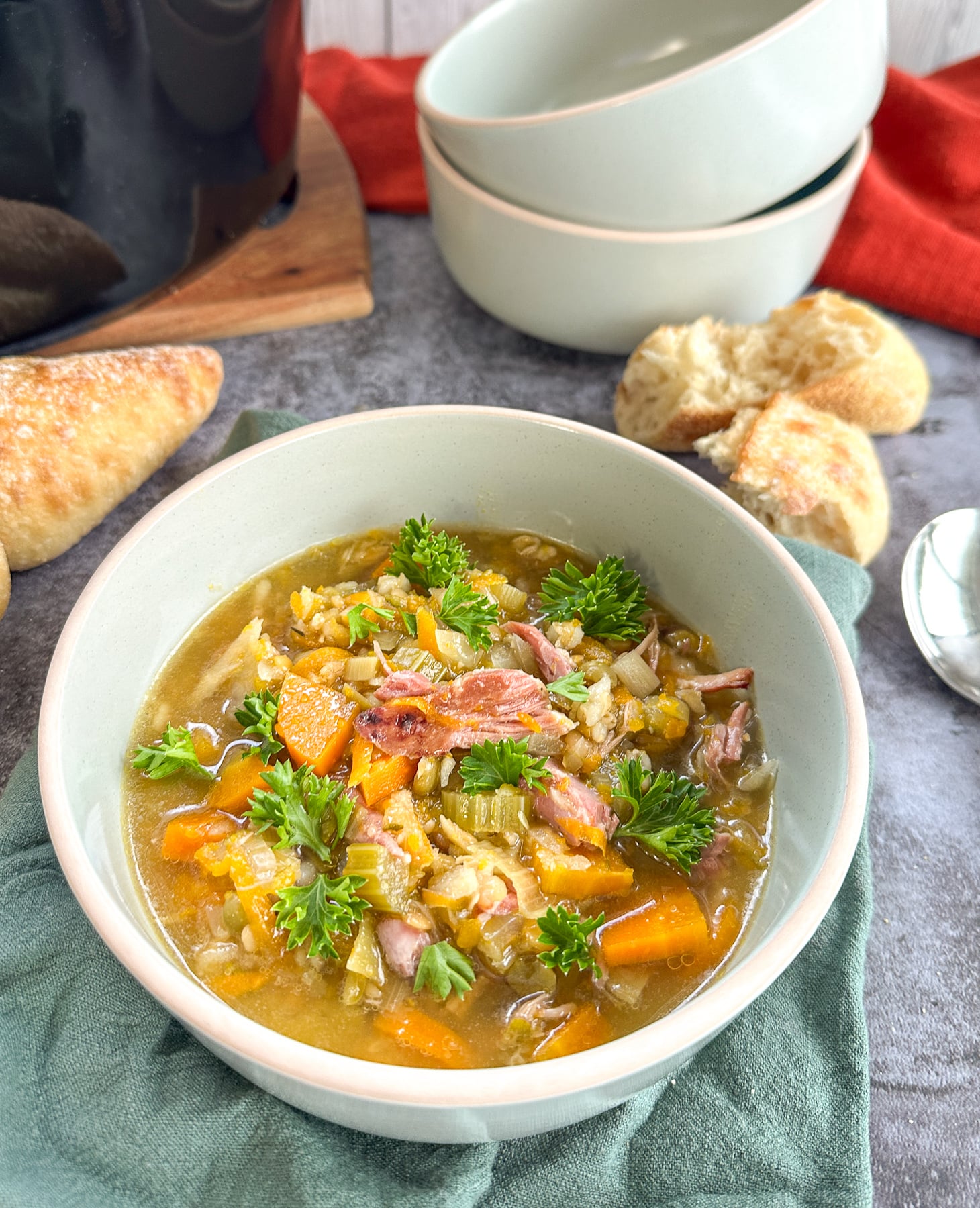 Bowl of slow cooker ham and vegetable soup with split peas and crusty bread