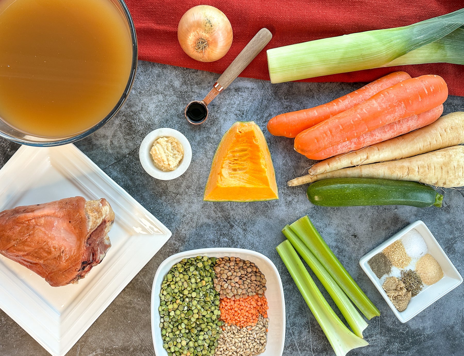 the ingredients for slow cooker ham hock vegetable soup including broth and split peas barley and lentils