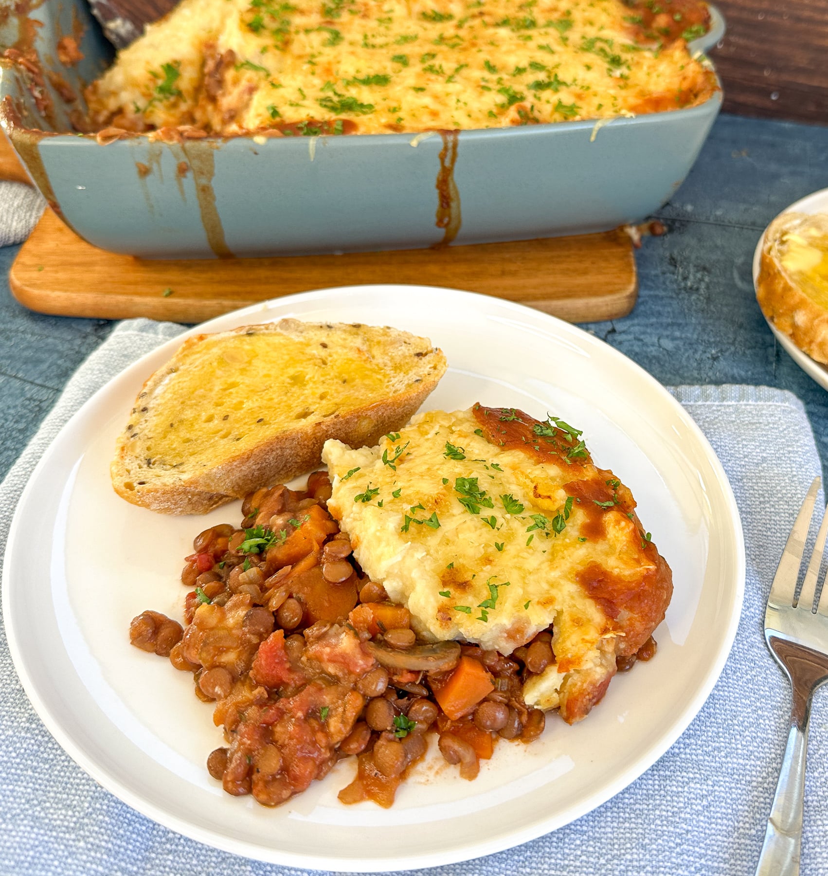 Plate full of vegetarian slow cooker lentil vegetarian cottage pie and crusty bread