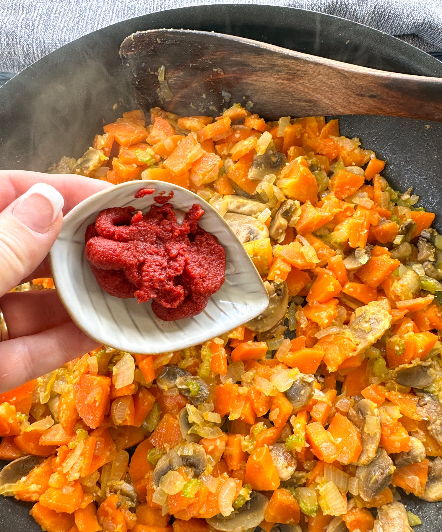adding tomato paste to the softened veges in the skillet