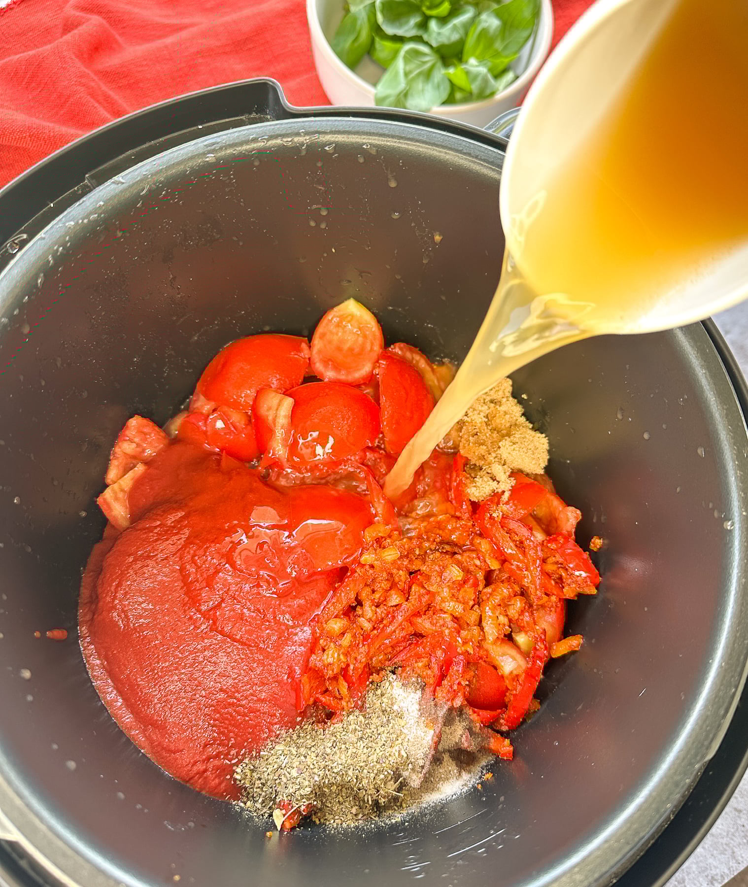 pouring broth into the tomato base soup