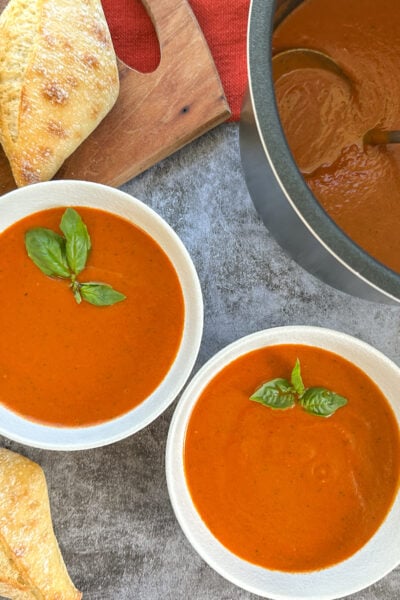 slow cooker tomato basil soup with crusty bread in two bowls