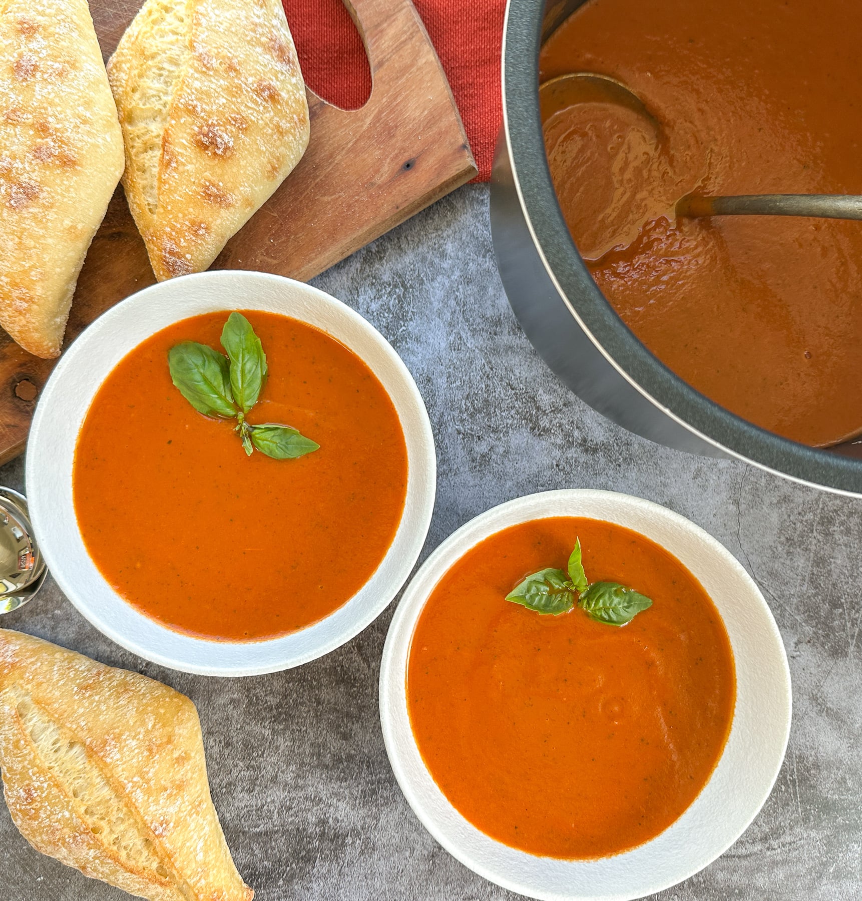 slow cooker tomato basil soup with crusty bread in two bowls
