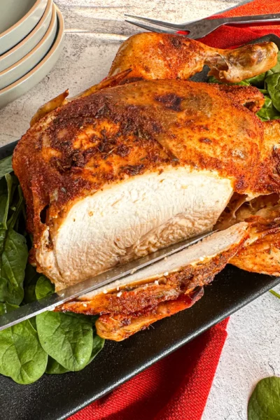 Slicing into a whole chicken that has been slow cooked in a rub