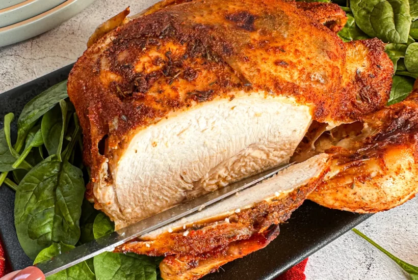 Slicing into a whole chicken that has been slow cooked in a rub