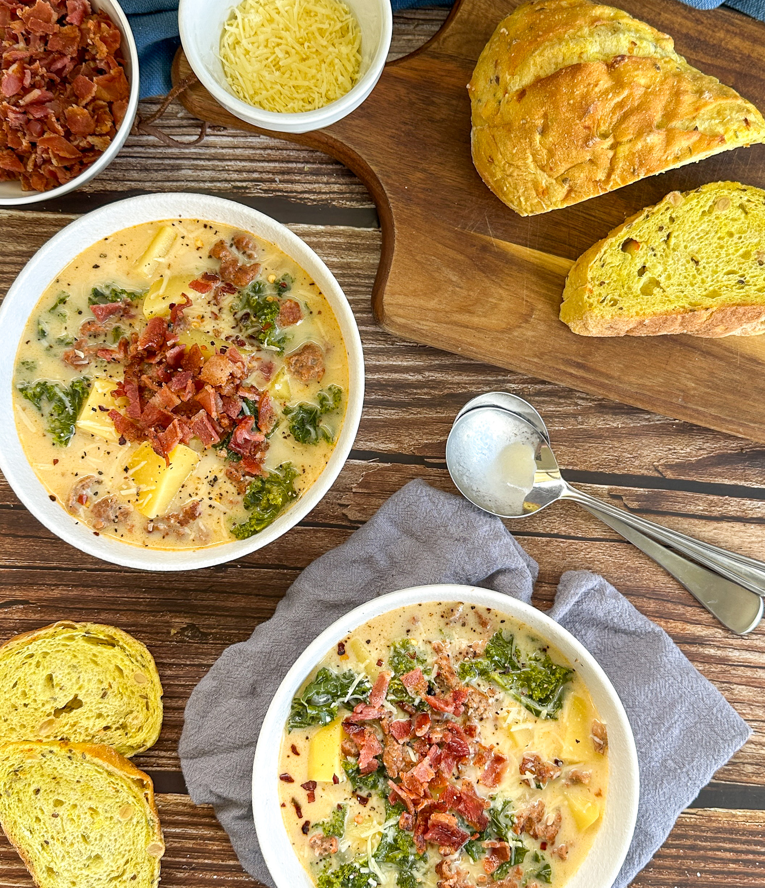 two bowls of cozy tuscan sausage and potato soup with crusty bread