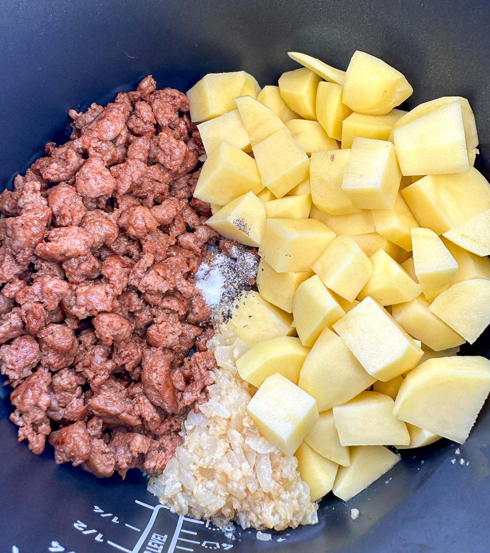potatoes, browned Italian sausage and sautéed onions and garlic and seasoning in the slow cooker ready for the broth for soup