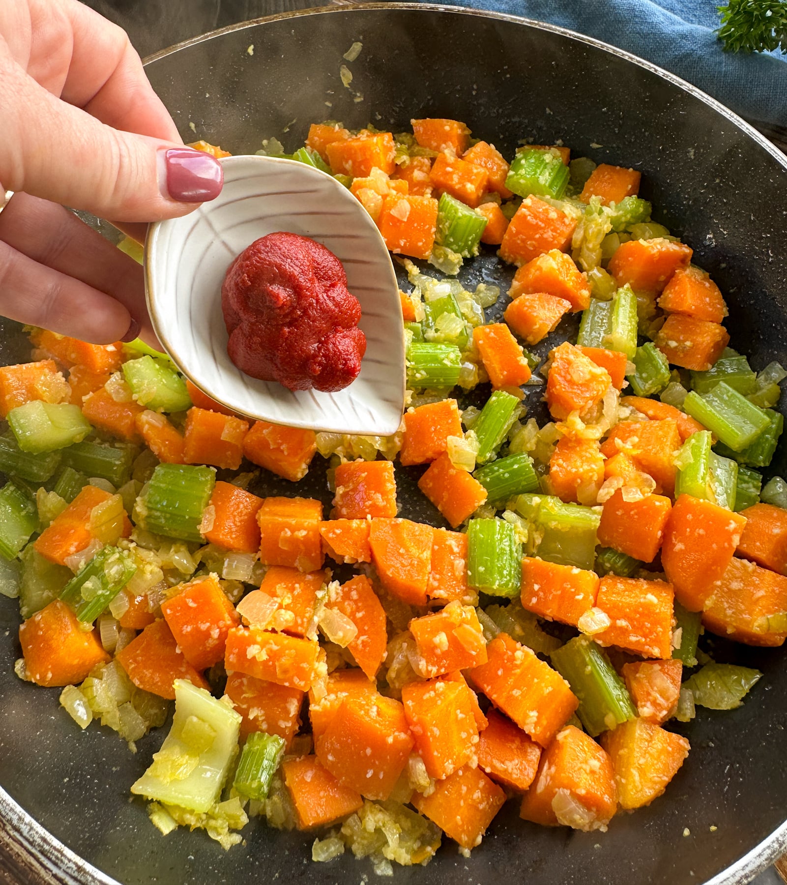 adding the tomato paste to the sautéed vegetables