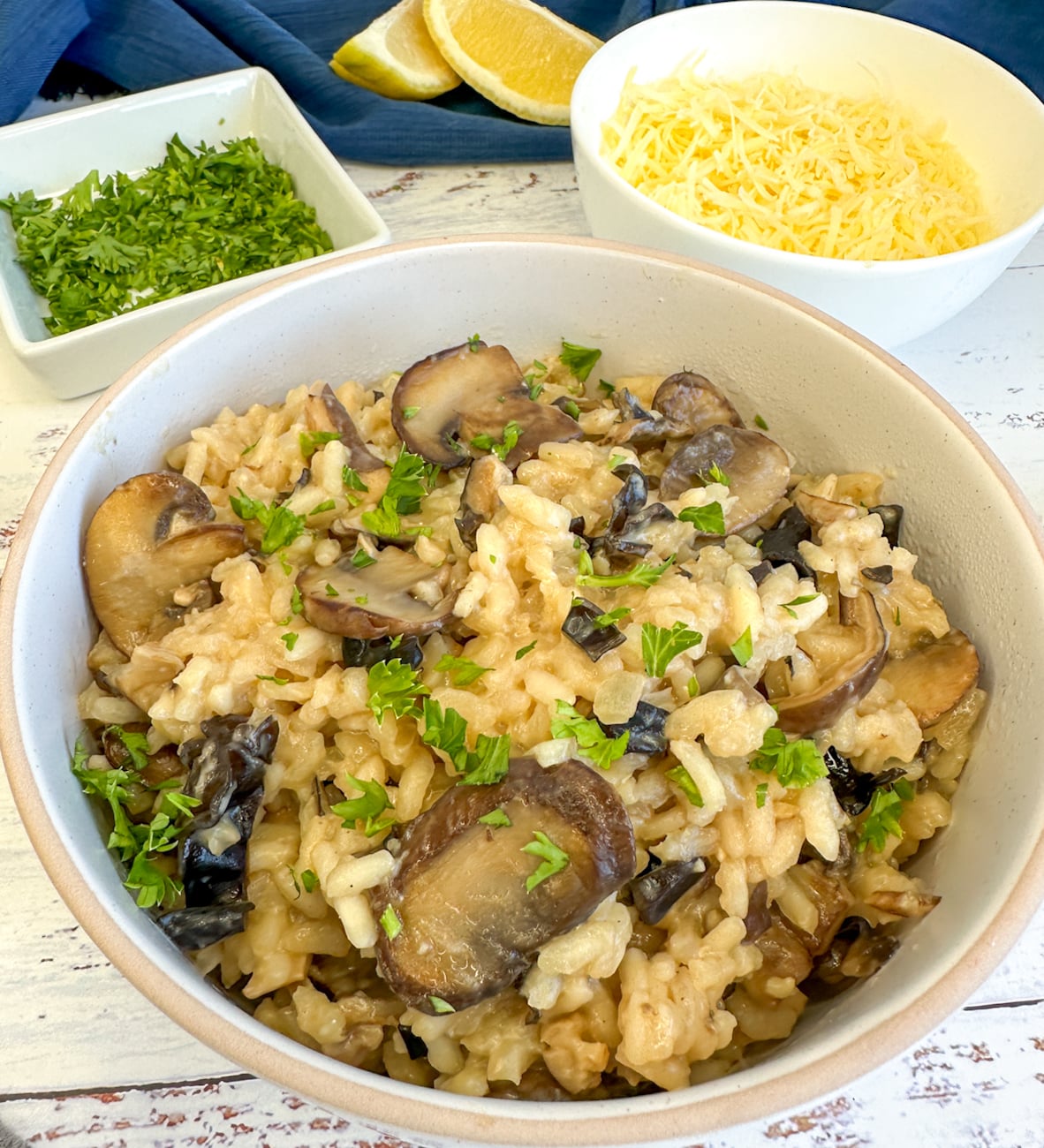 Bowl of slow cooker mushroom risotto with a wedge of lemon parsley and parmesan