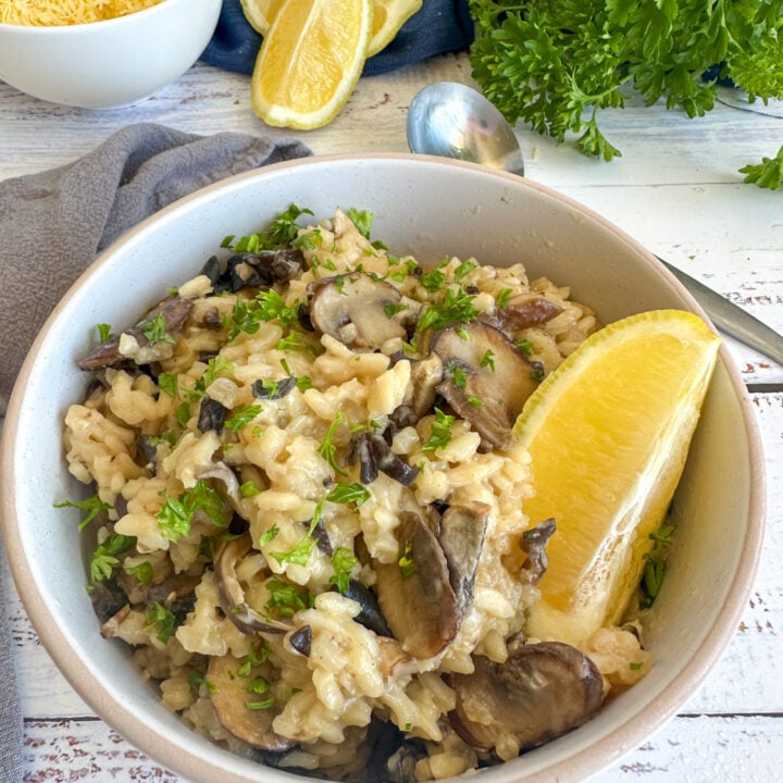 Bowl of slow cooker mushroom risotto with a wedge of lemon