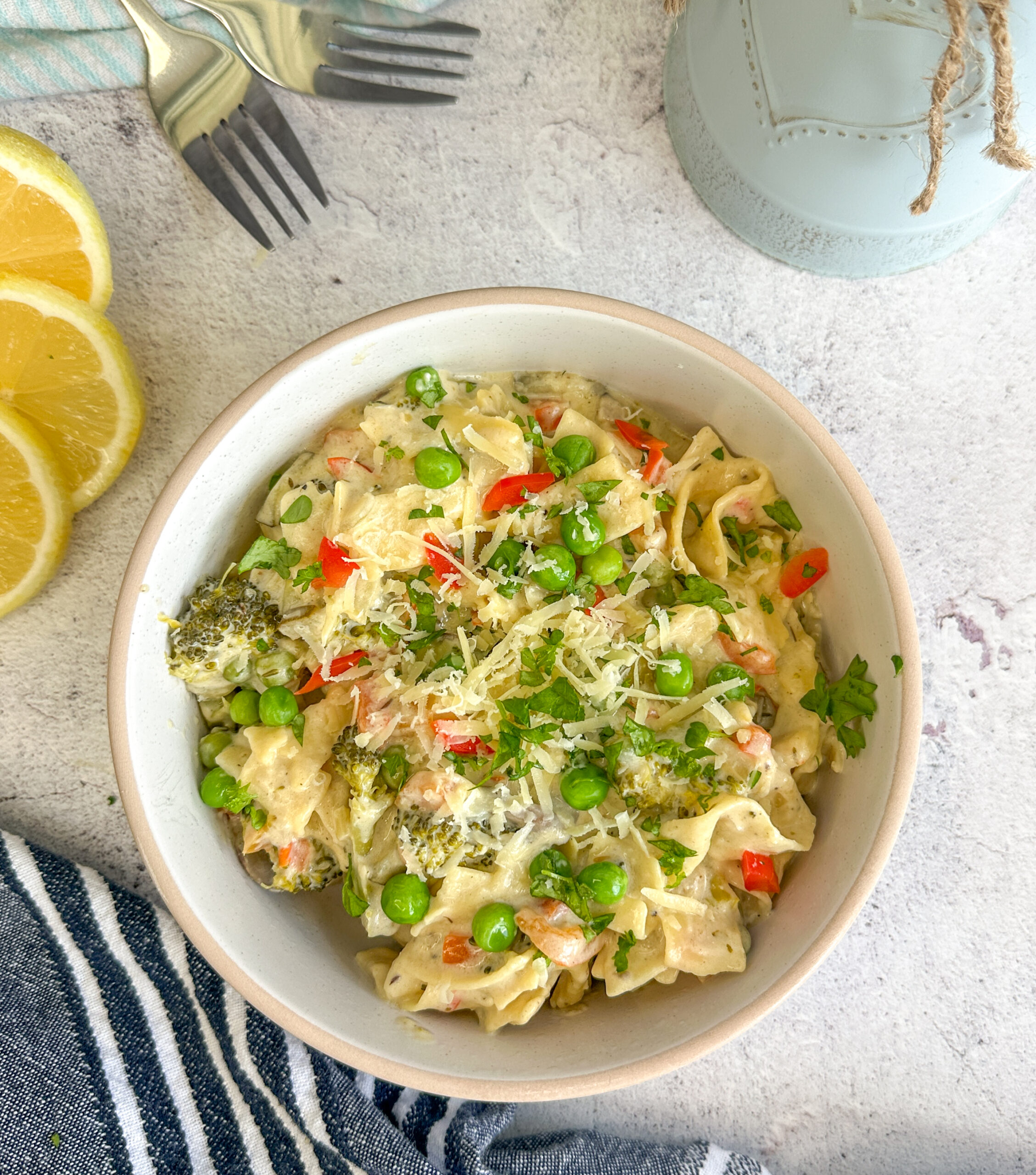 bowl of creamy vegetable alfredo with lemon slices and parsley