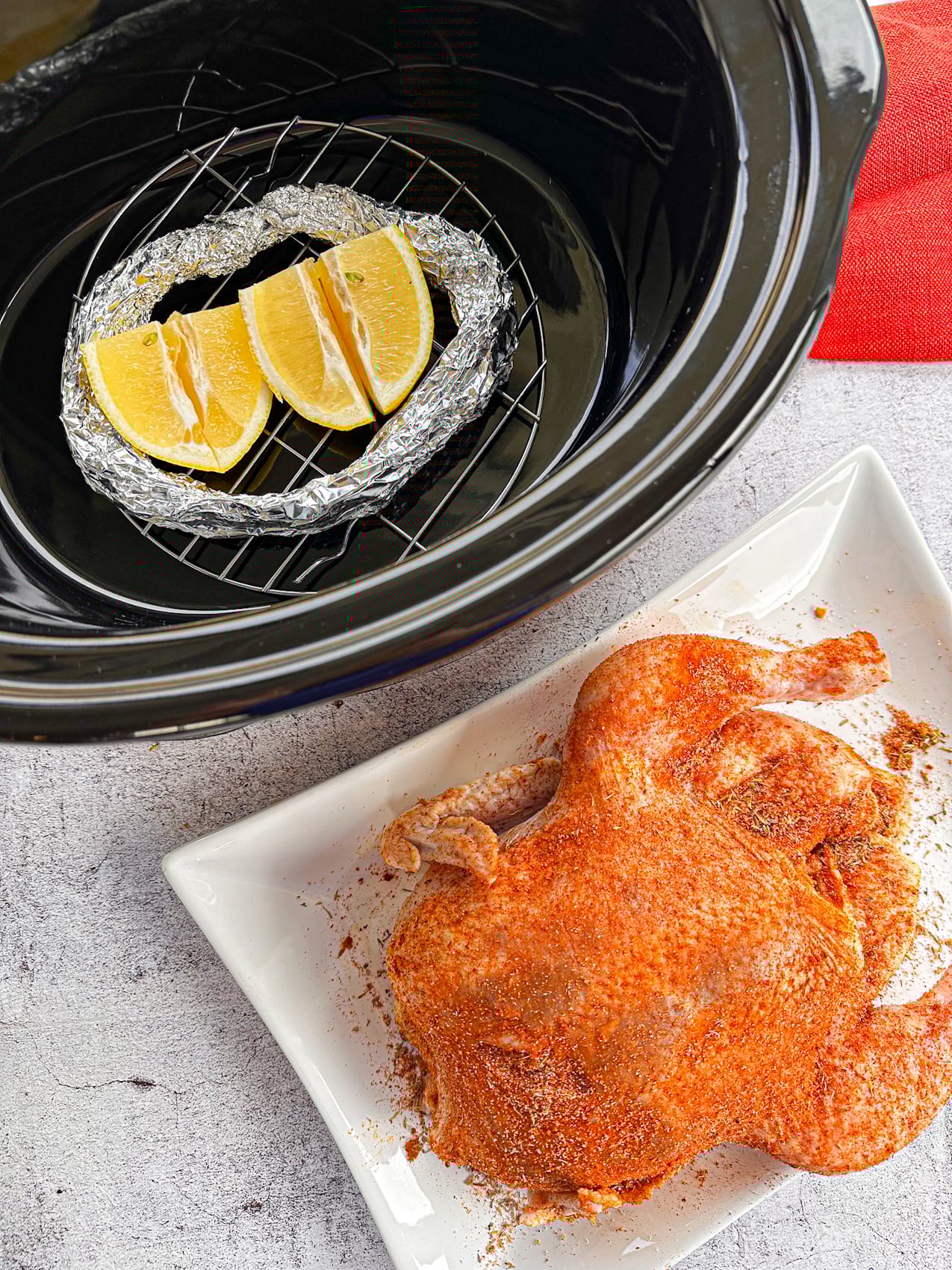 adding a foil ring and lemons to the base of the slow cooker to lift the chicken off the base
