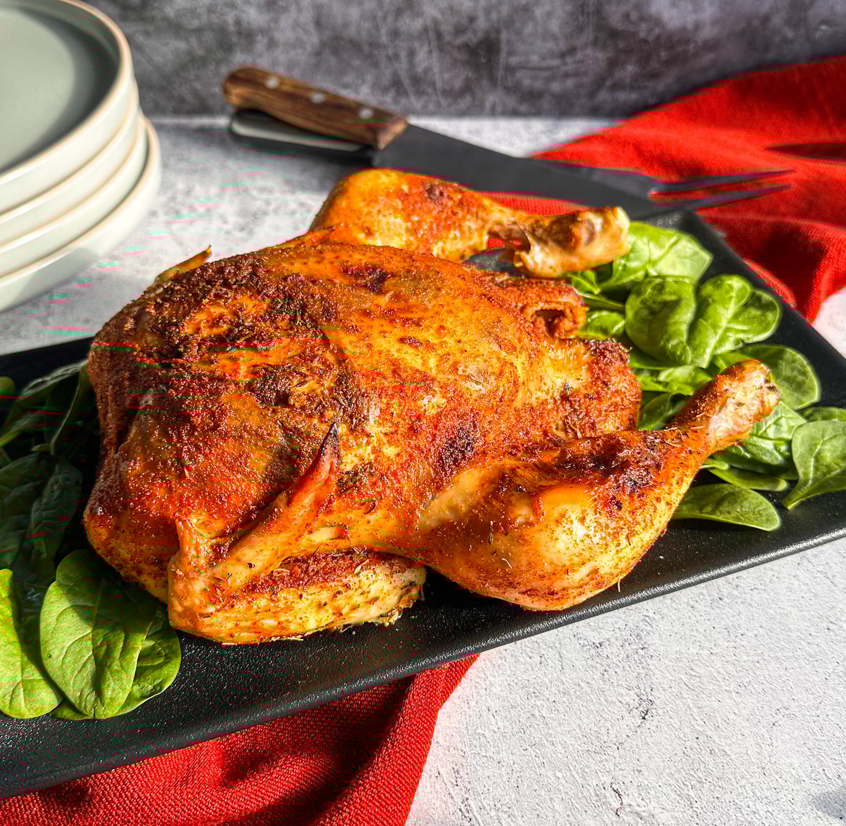 whole slow cooker chicken with golden crispy skin on a bed of spinach