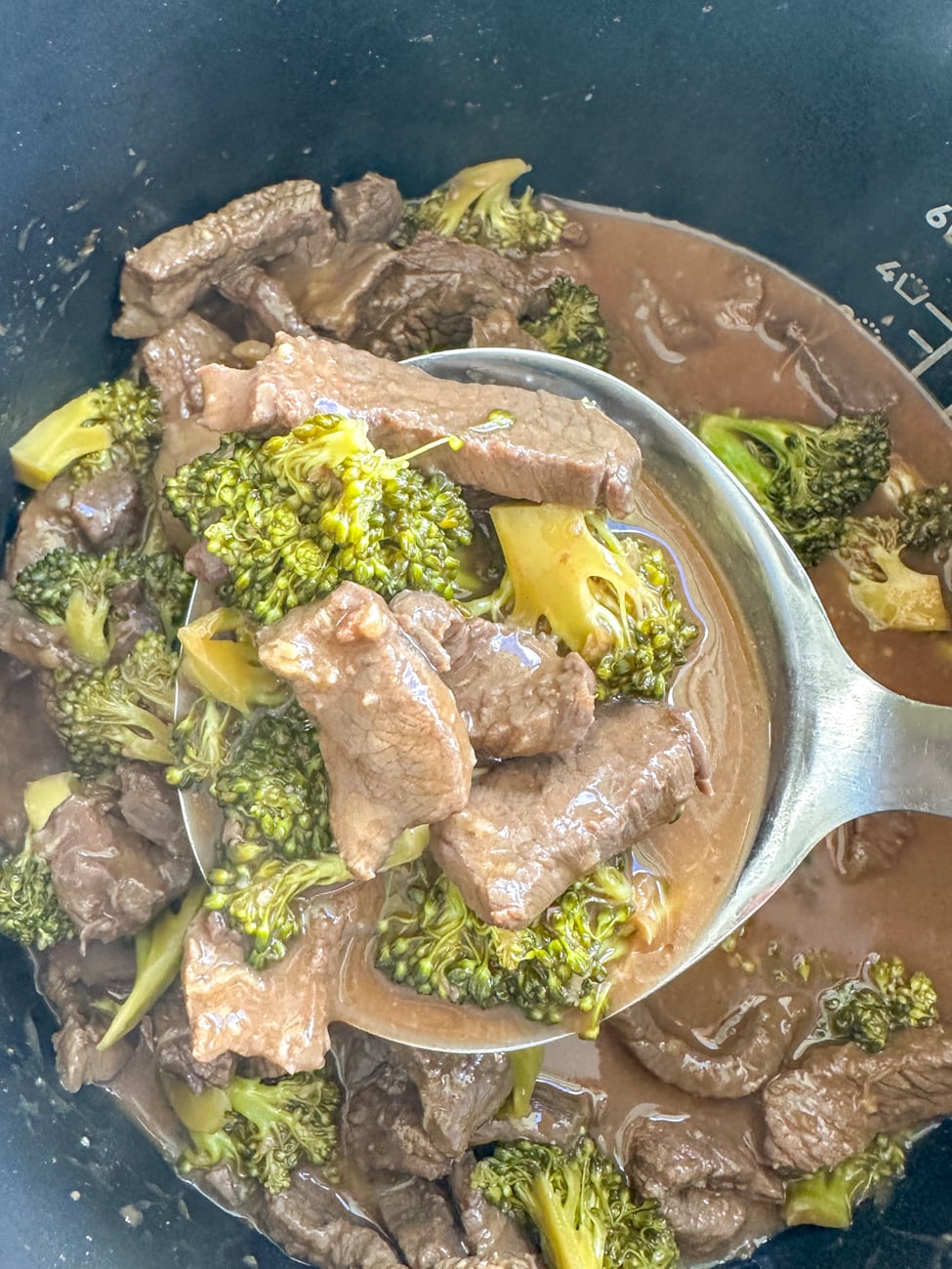 ladle full of beef and broccoli with takeaway style sauce