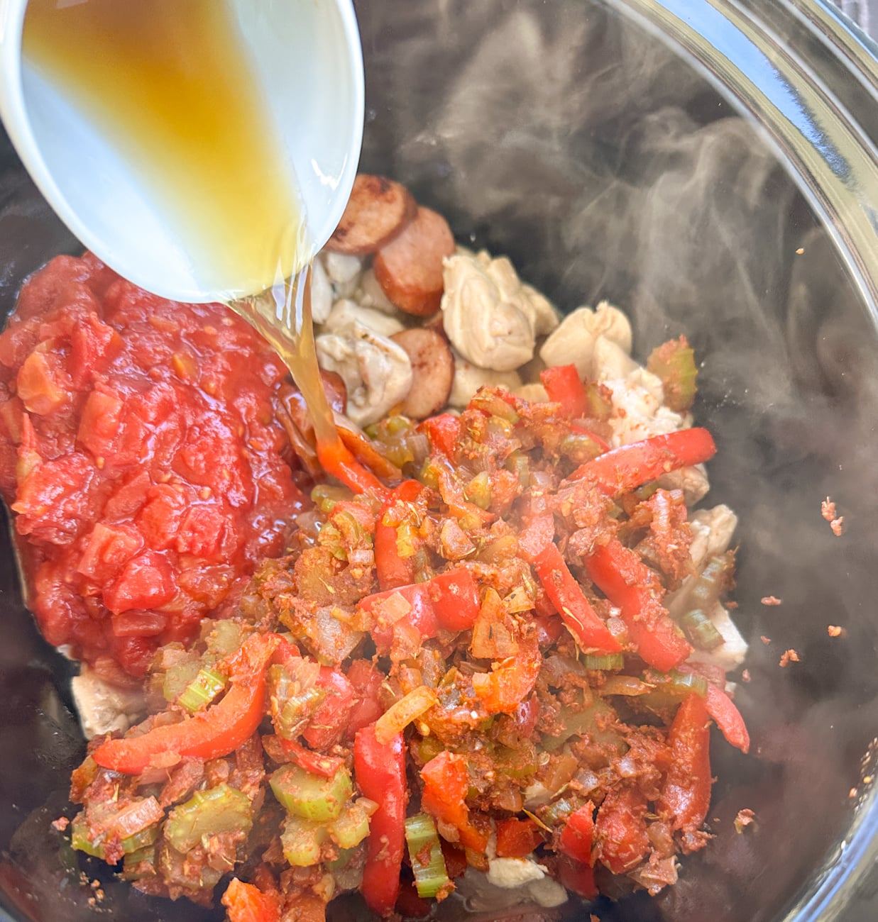 adding all the ingredients to the slow cooker for the jambalaya