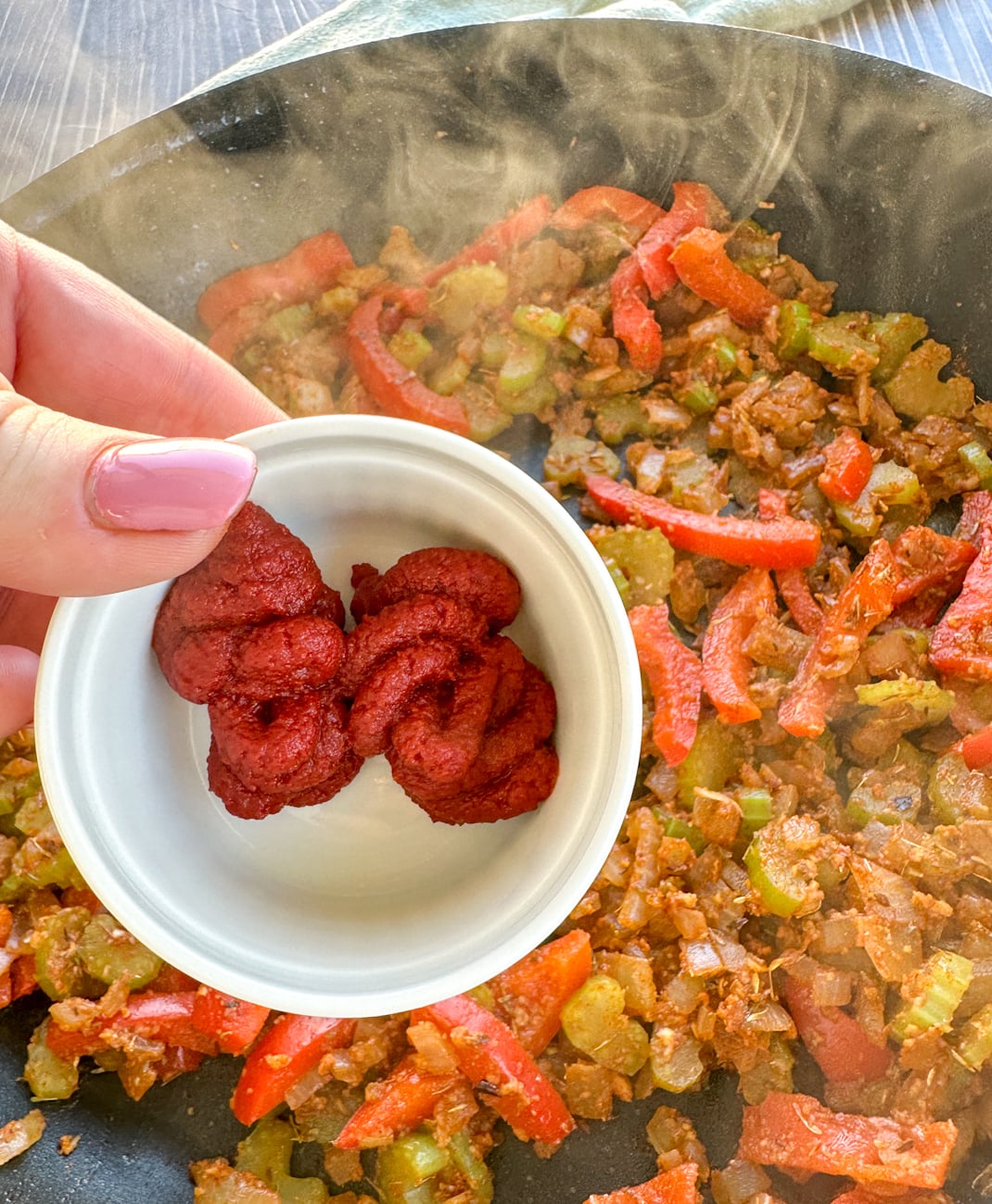 adding the tomato paste to deepen the dish
