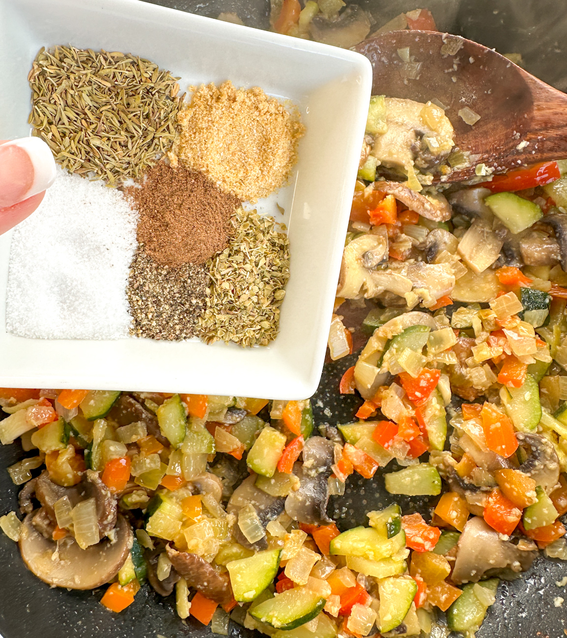 adding herbs to the sauteed vegetables