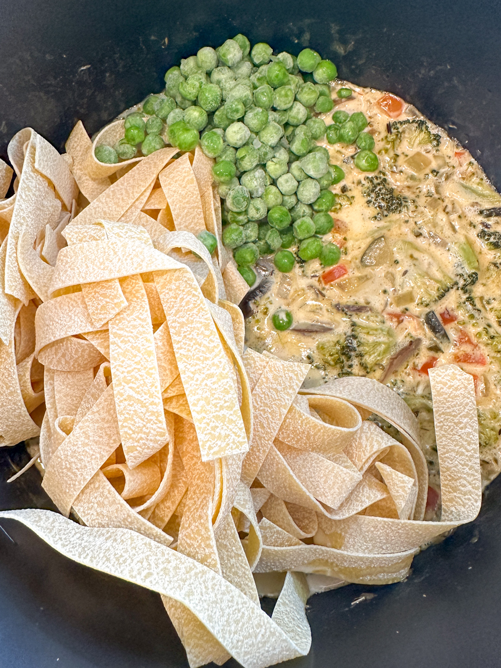 adding the peas and brocolli to the slow cooker creamy sauce
