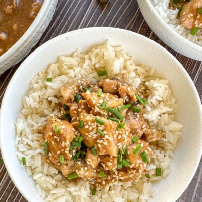 Bowl of honey soy chicken over rice with sesame seeds