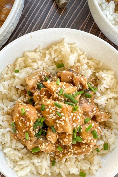 Bowl of honey soy chicken over rice with sesame seeds