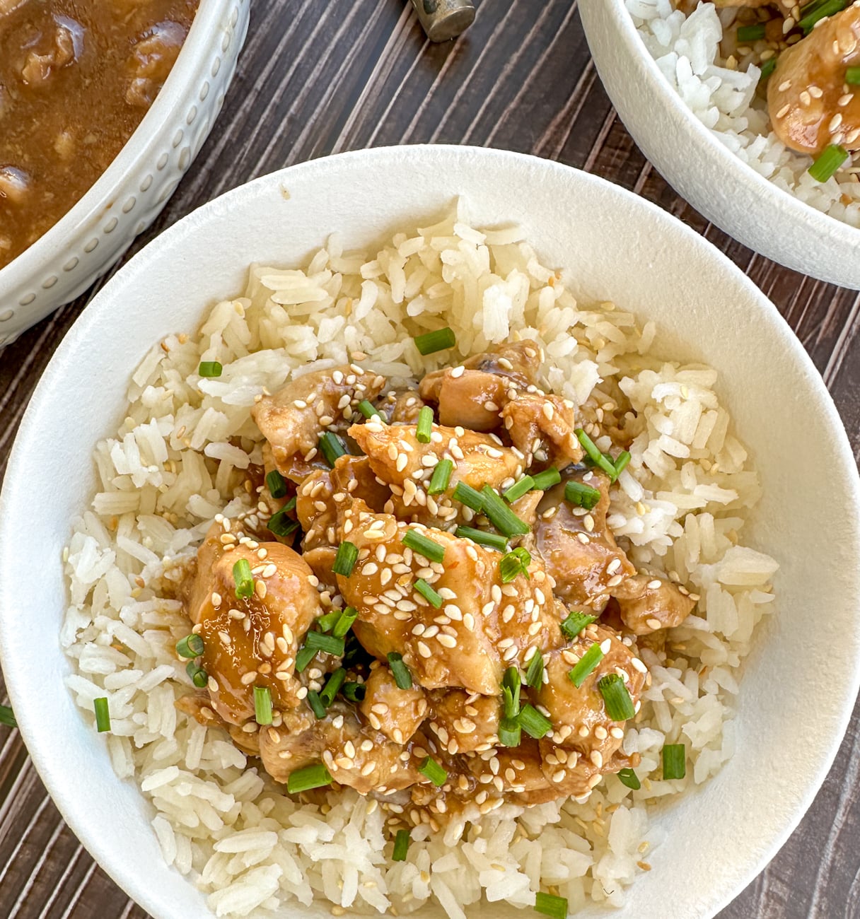 Bowl of honey soy chicken over rice with sesame seeds