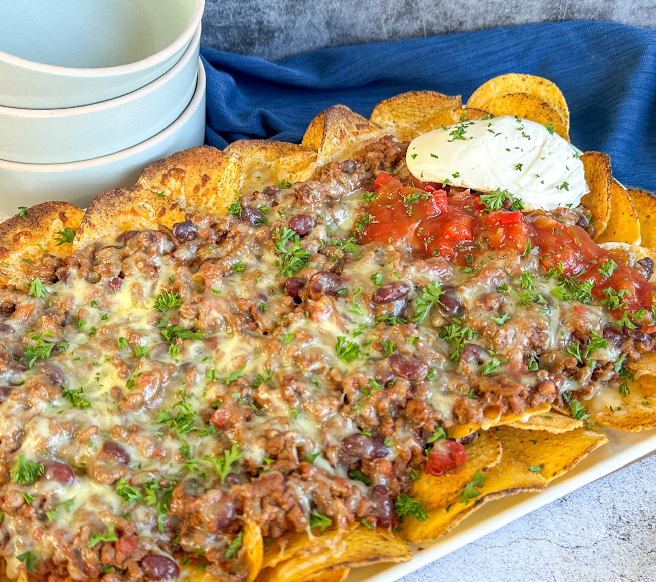 platter with cornchips overlaid with slow cooker beef chilli nacho mix cheese and sour cream