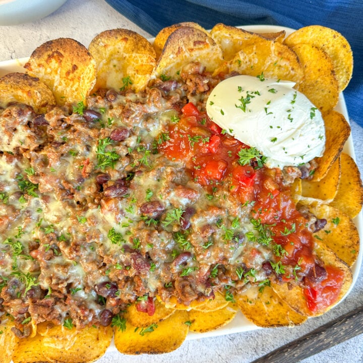 finished beef nacho chilli served over corn chips, with melted cheese sour cream and salsa