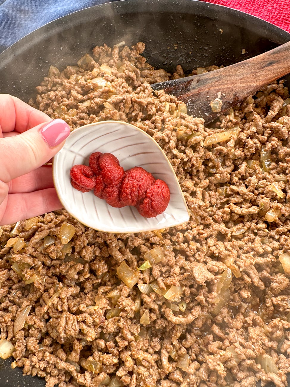adding tomato paste to beef mince