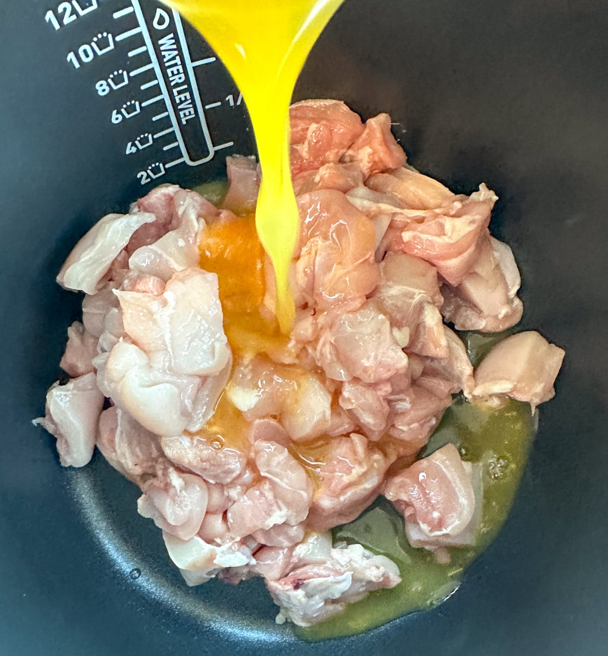pouring the orange sauce into the chicken int he slow cooker