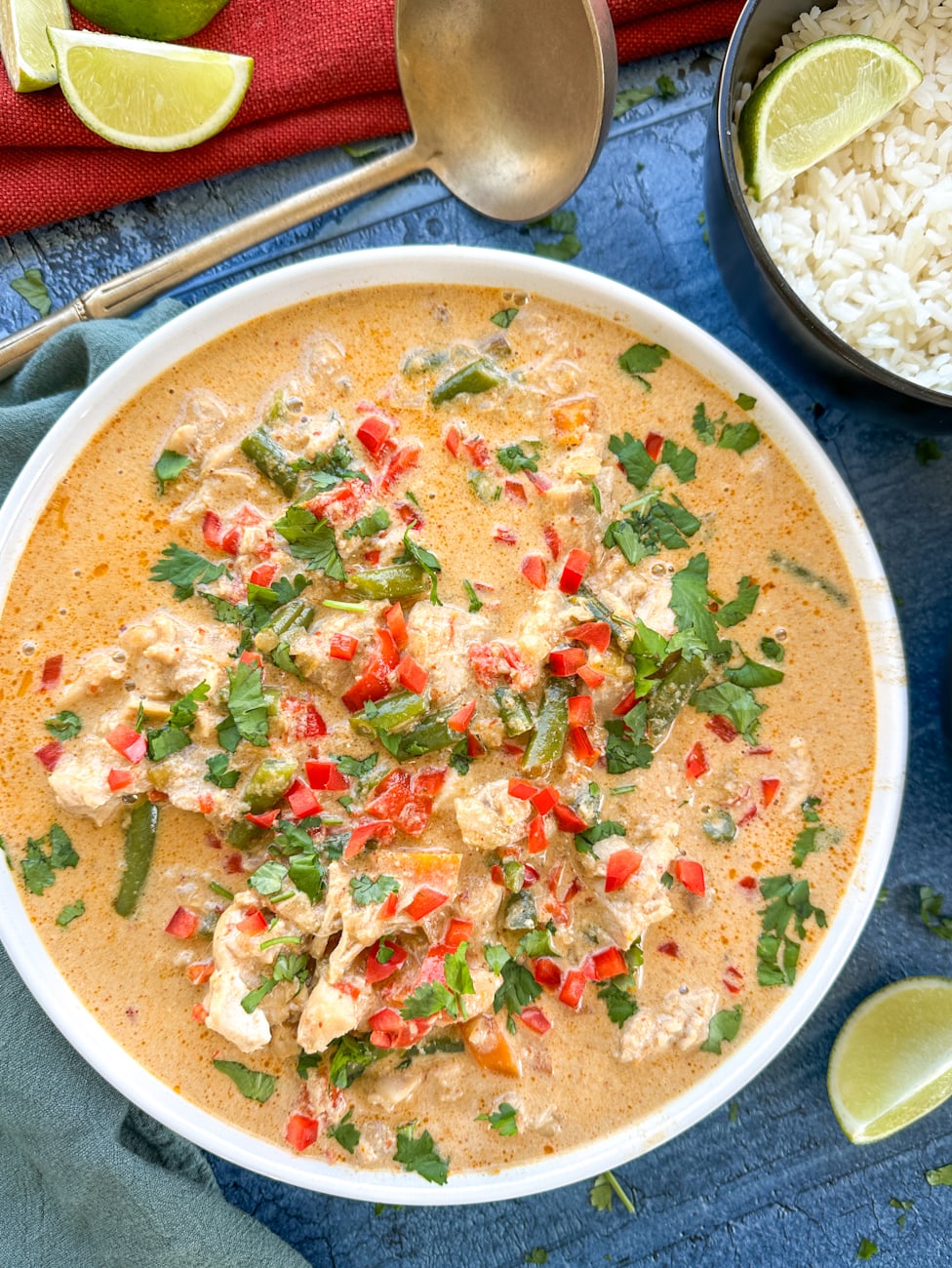 bowl of red thai curry with rice and limes