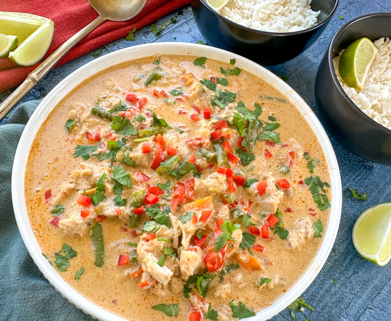 large bowl of slow cooker red thai chicken curry ready to serve over bowls of rice