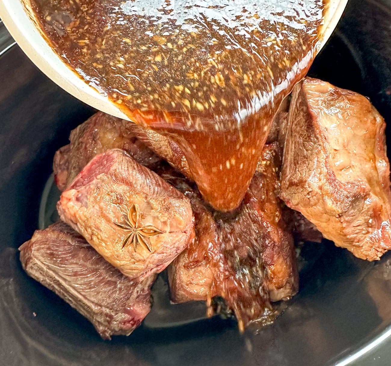 pouring sauce over shortribs before cooking