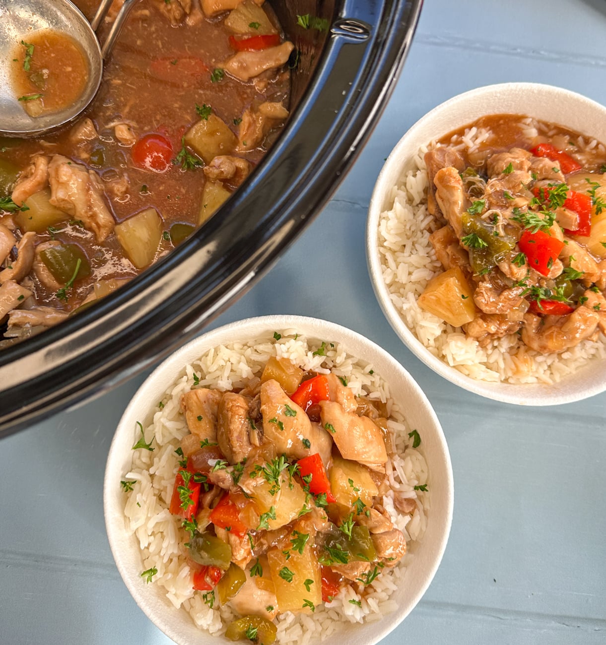 Slow Cooker with sweet and sour chicken and two bowls served over rice