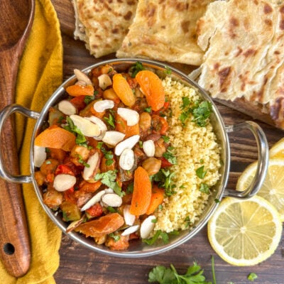 Metal serving dish with coucous and moroccan tagine served with apricots, almonds and lemon slices