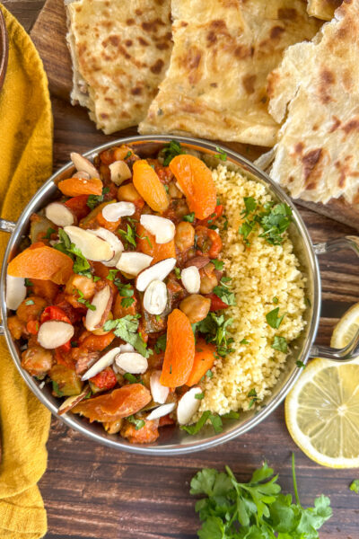 Metal serving dish with coucous and moroccan tagine served with apricots, almonds and lemon slices