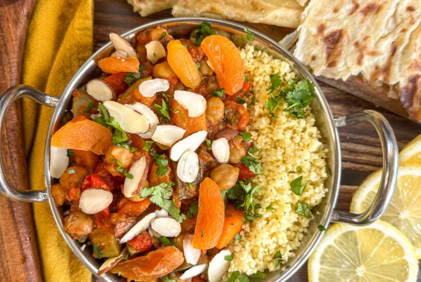 Metal serving dish with coucous and moroccan tagine served with apricots, almonds and lemon slices