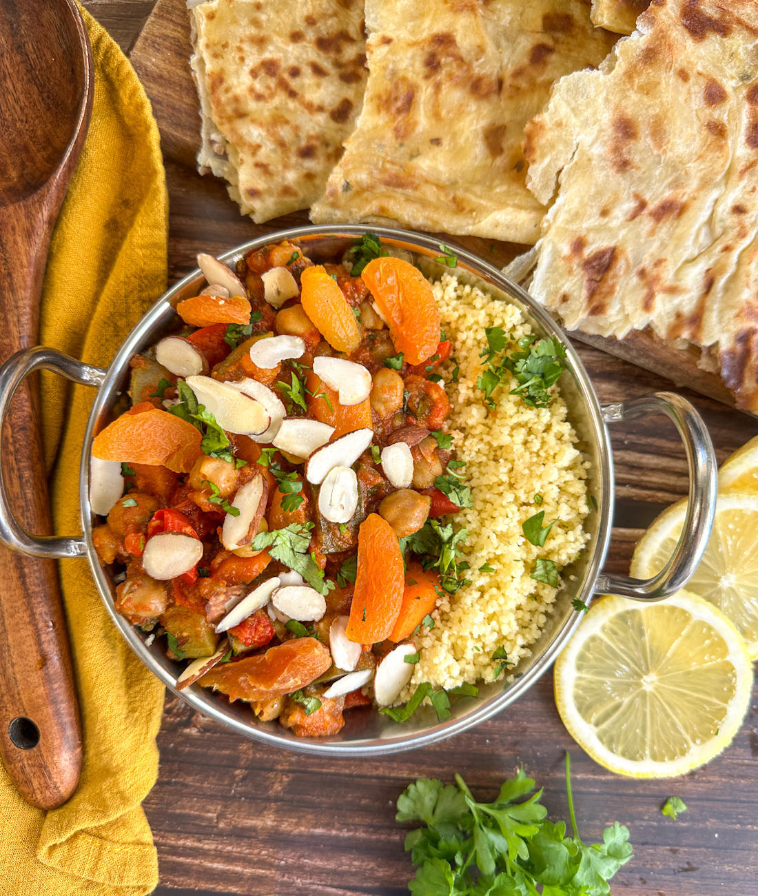 Metal serving dish with coucous and moroccan tagine served with apricots, almonds and lemon slices