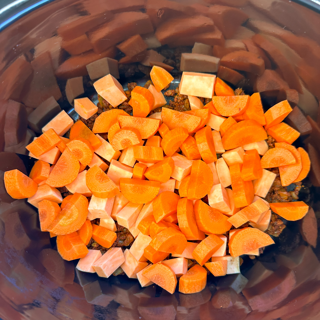adding carrots and kumara to the base of the slow cooker