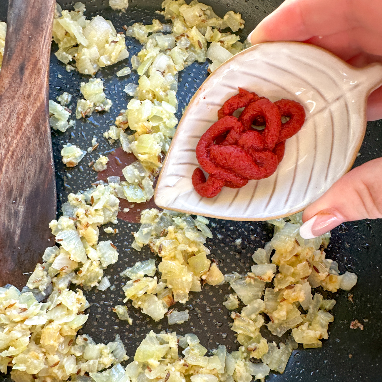 adding tomato paste to sauteed onions