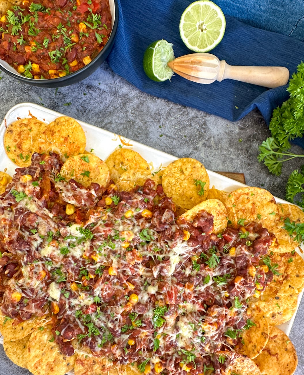 platter of tortilla chips with vegetarian chili beans covered in melted cheese