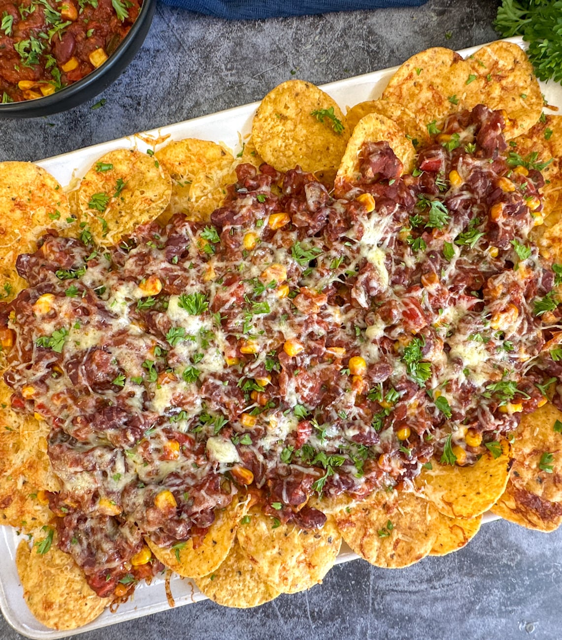 Slow Cooker Vegetarian Chili Nachos covered in cheese and parsley